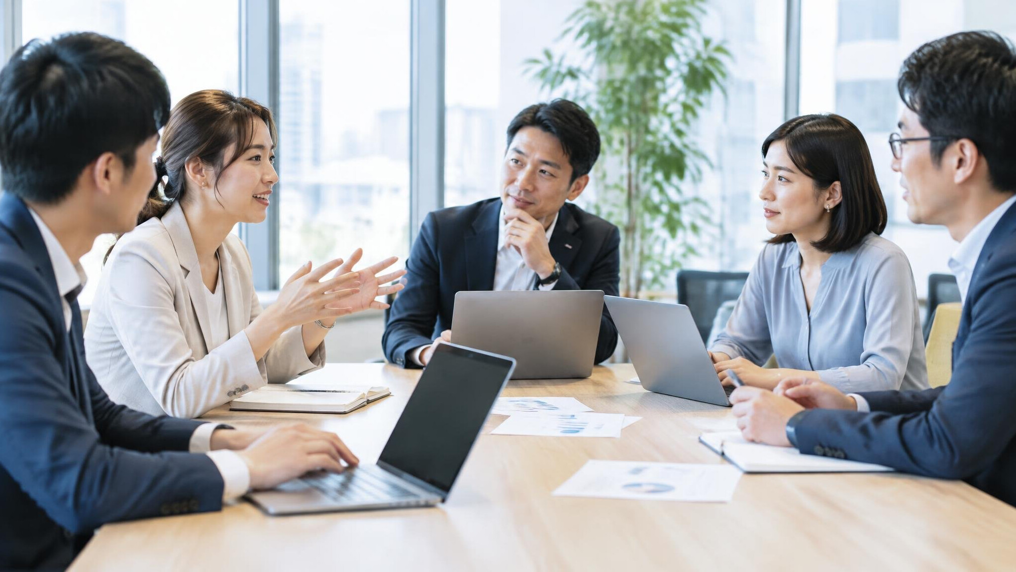 Japanese business team having a meeting around a table with laptops and documents